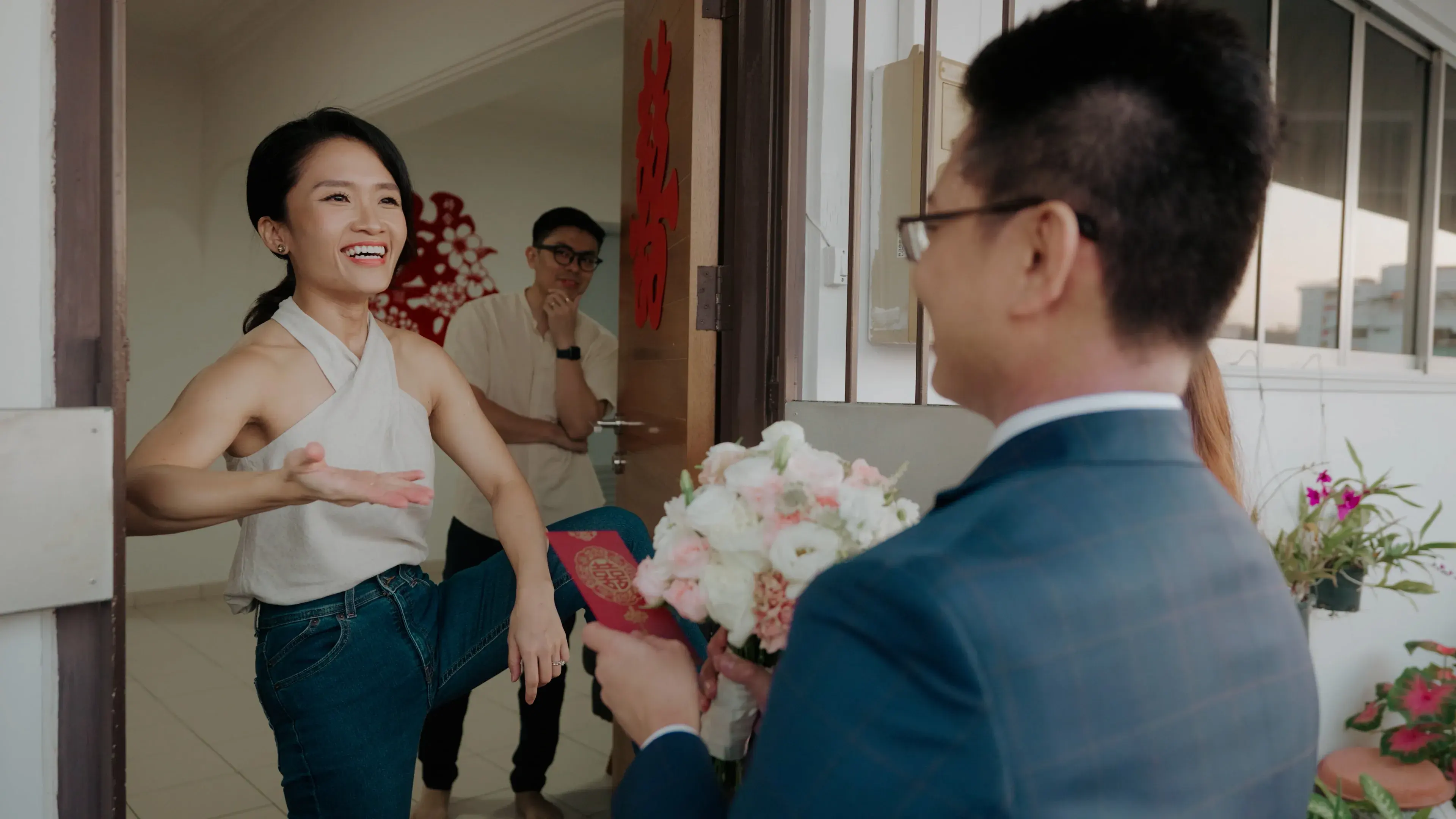 A bridesmaid greeting the groom at the doorway during the wedding morning