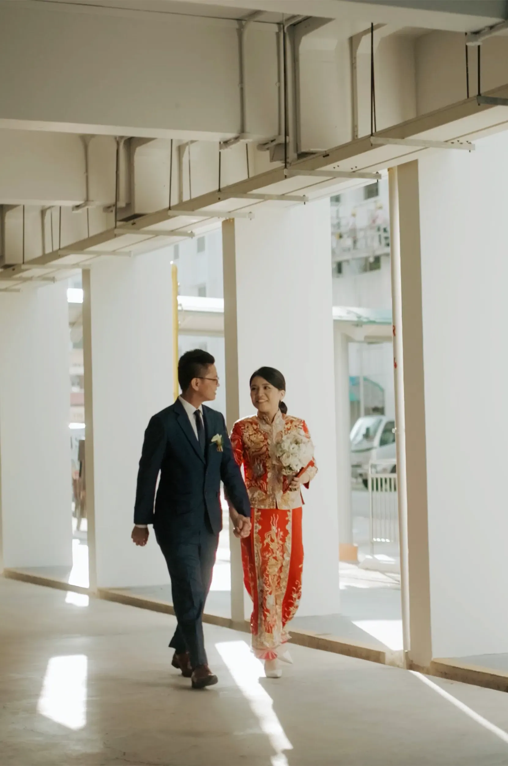Gee Chuan and Min Xian walking together through the HDB corridor on their wedding day